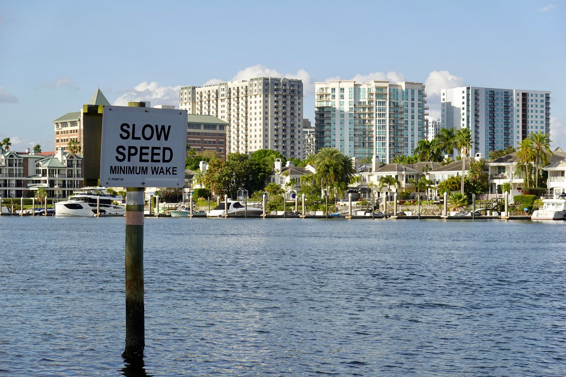 A picturesque view of downtown Tampa's waterfront with a 'Slow Speed' sign and modern buildings in the background.