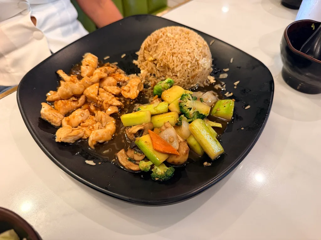 Chicken hibachi plate with fried rice and sautΓ©ed vegetables on black ceramic