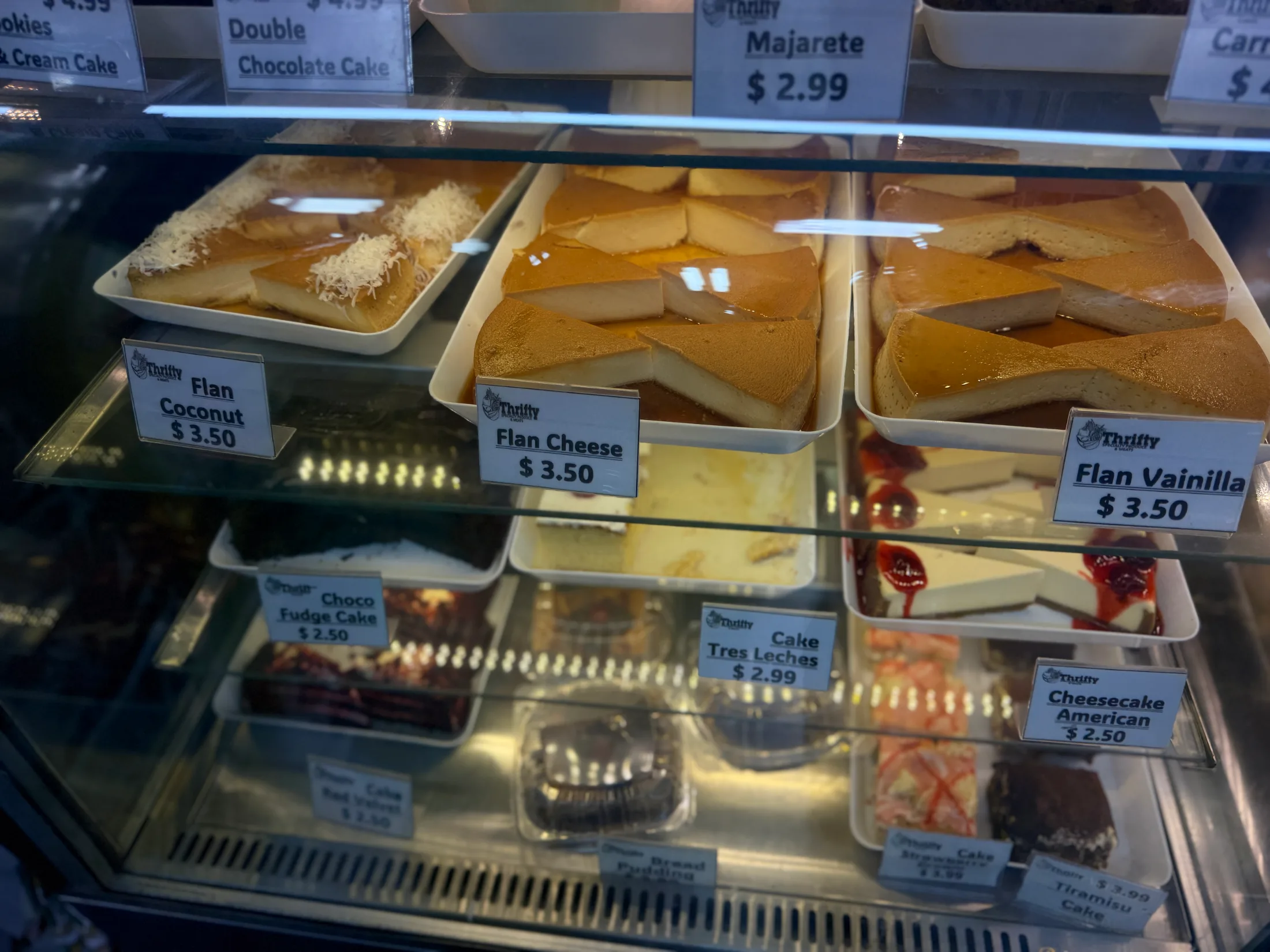 Savory food display case at Thrifty showing empanadas, tequeños, pastelitos, and other Latin snacks with price labels