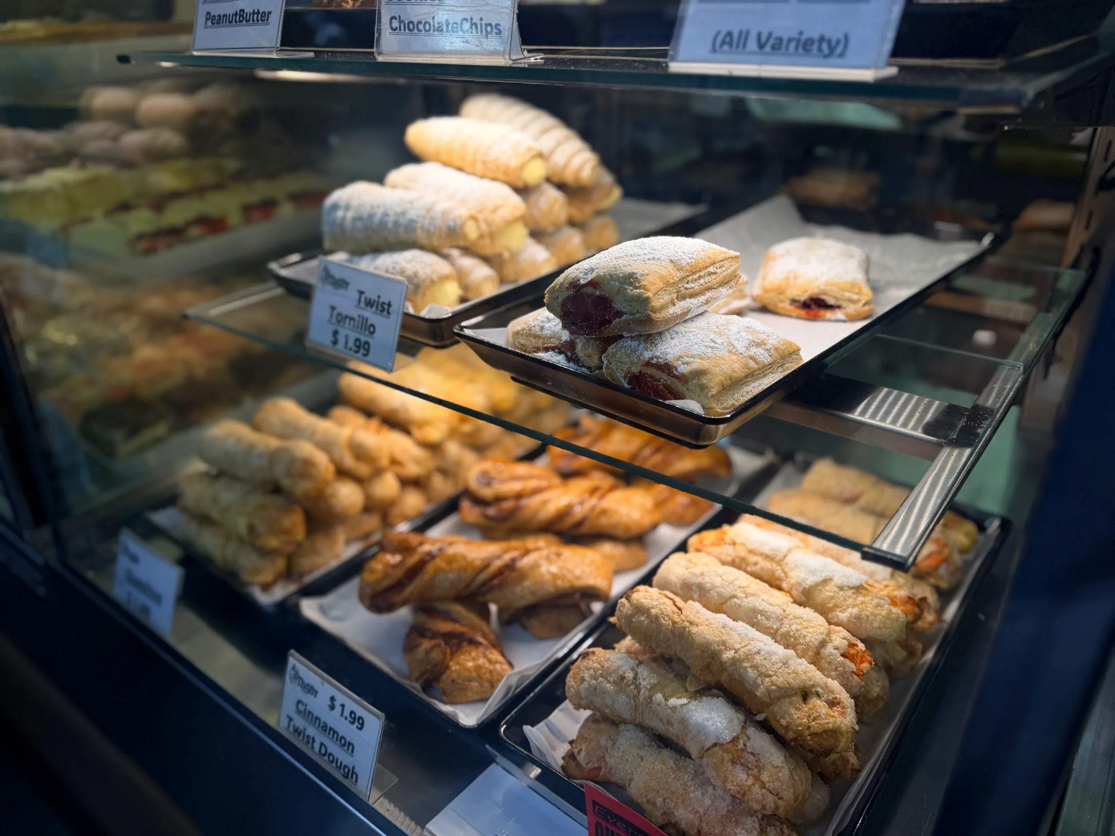 Bakery display case at Thrifty showing pastries including Twist Tornillo and puff pastries dusted with powdered sugar