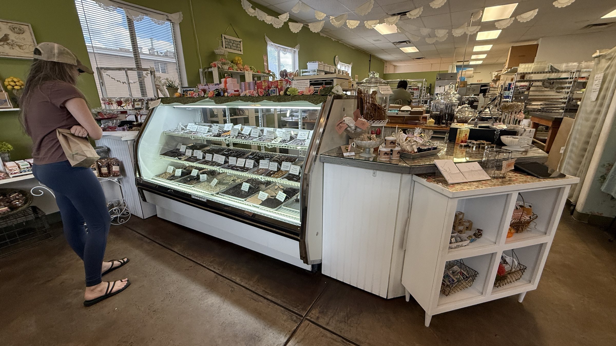 The inside of ChocolateSmith, with a glass case of chocolates in the middle of the shop and shelves of boxed chocolates