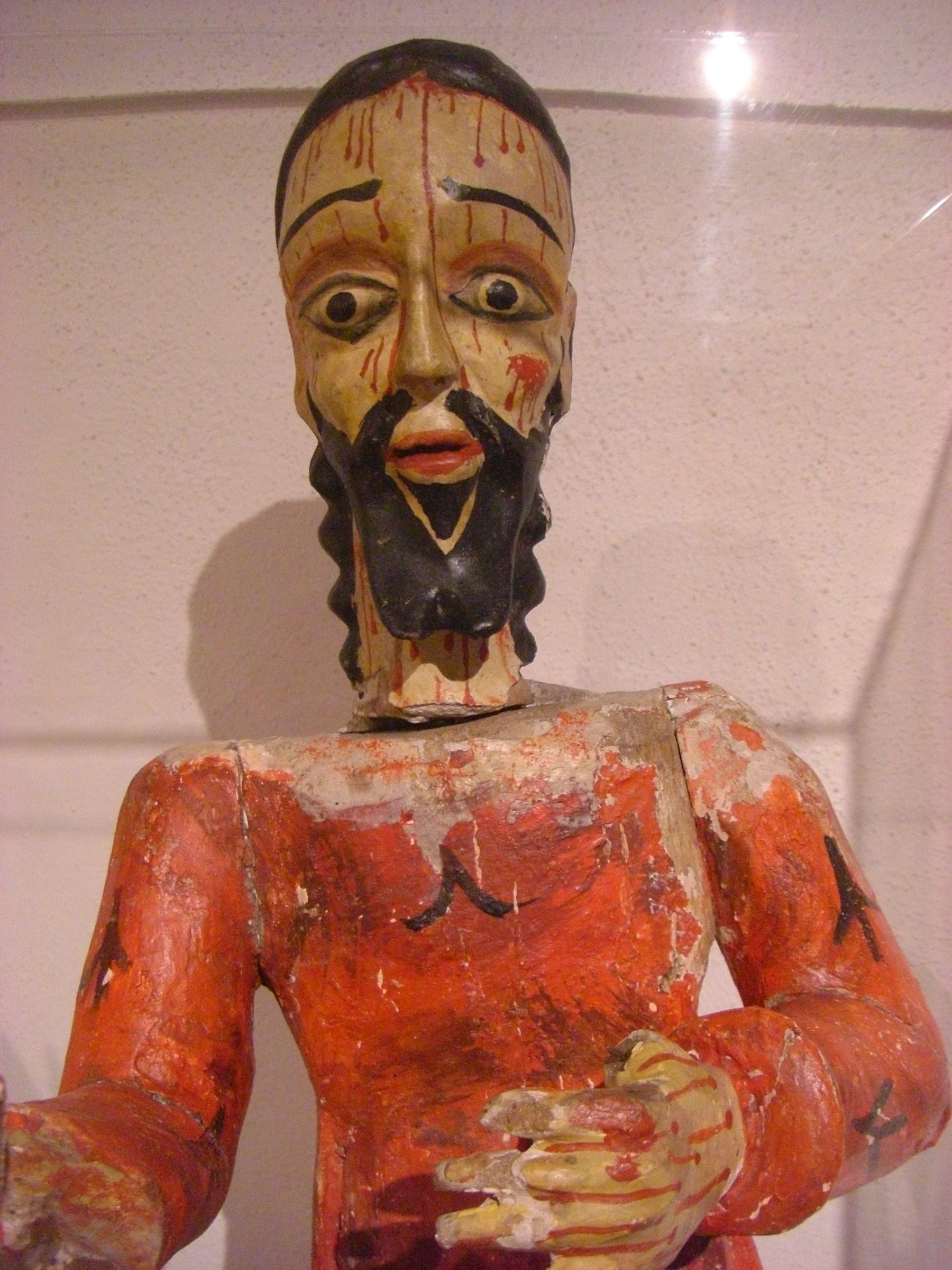 A carved and painted wooden saint figure with a dark beard and an orange robe, a Spanish colonial bulto at the Harwood Museum of Art