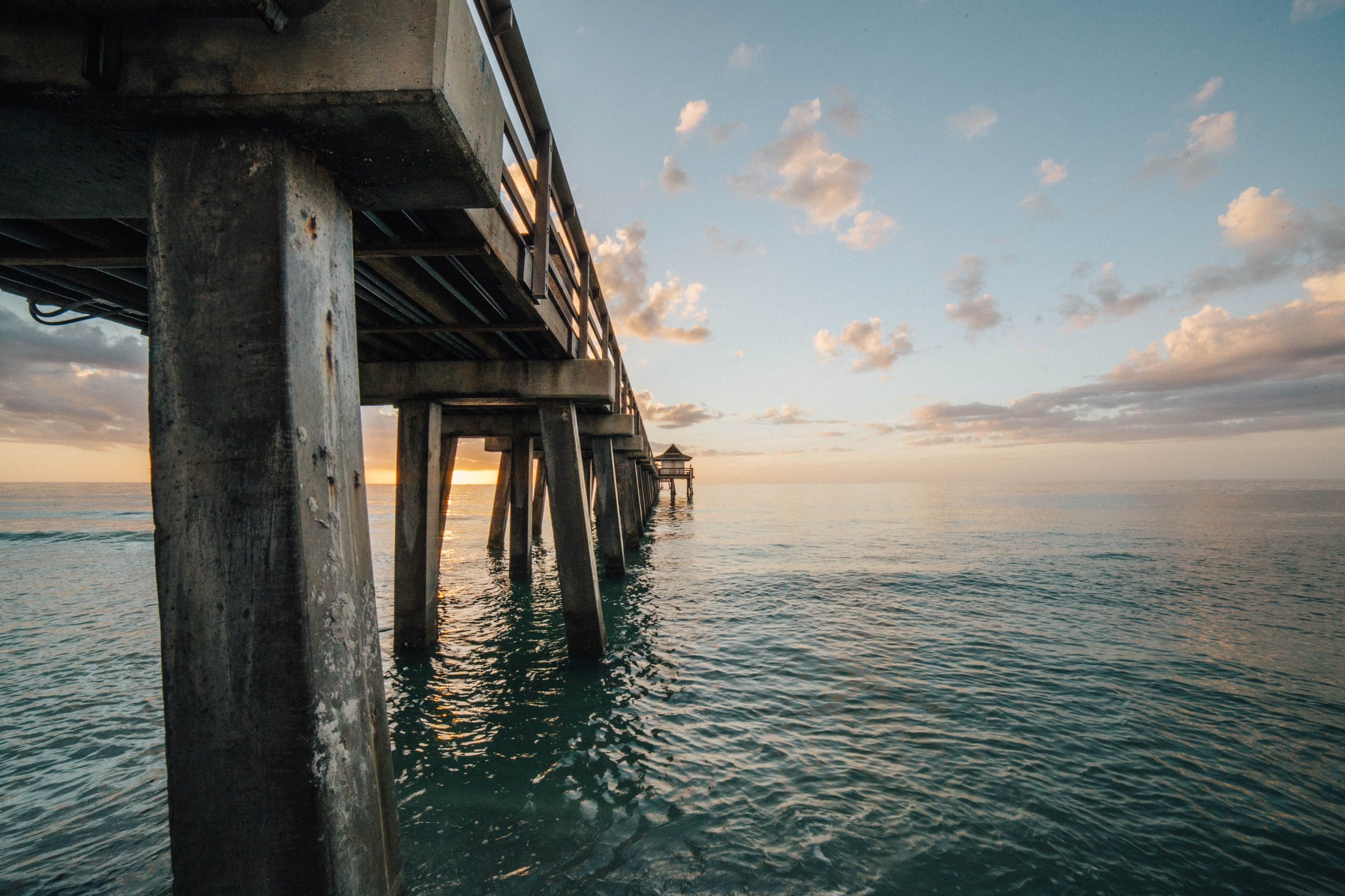 Sunset view of Naples Pier, Florida, over calm ocean waters