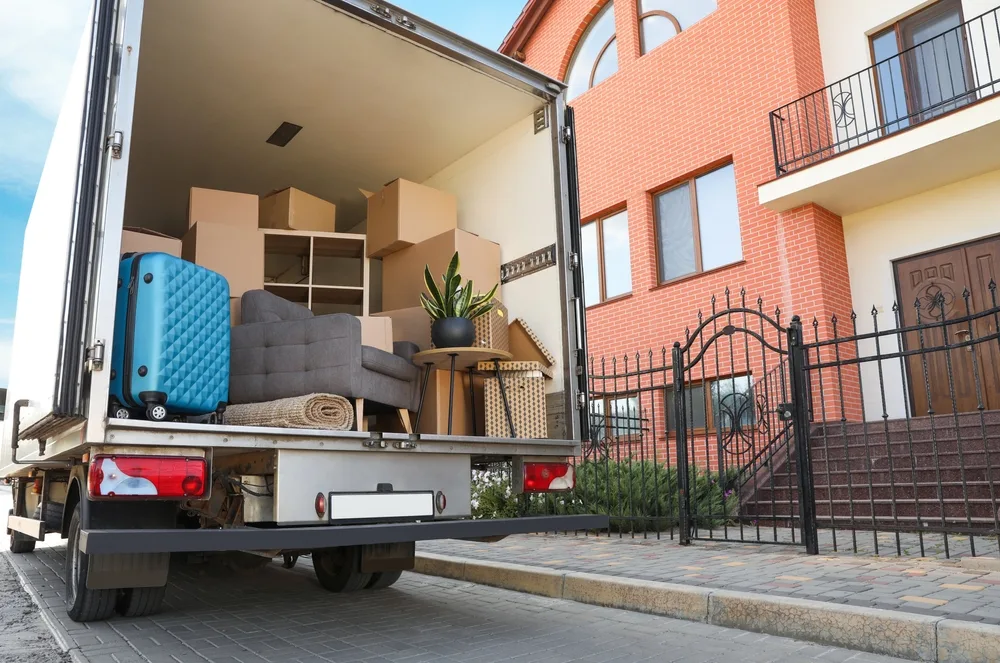 Moving truck loaded with furniture and boxes outside a brick house