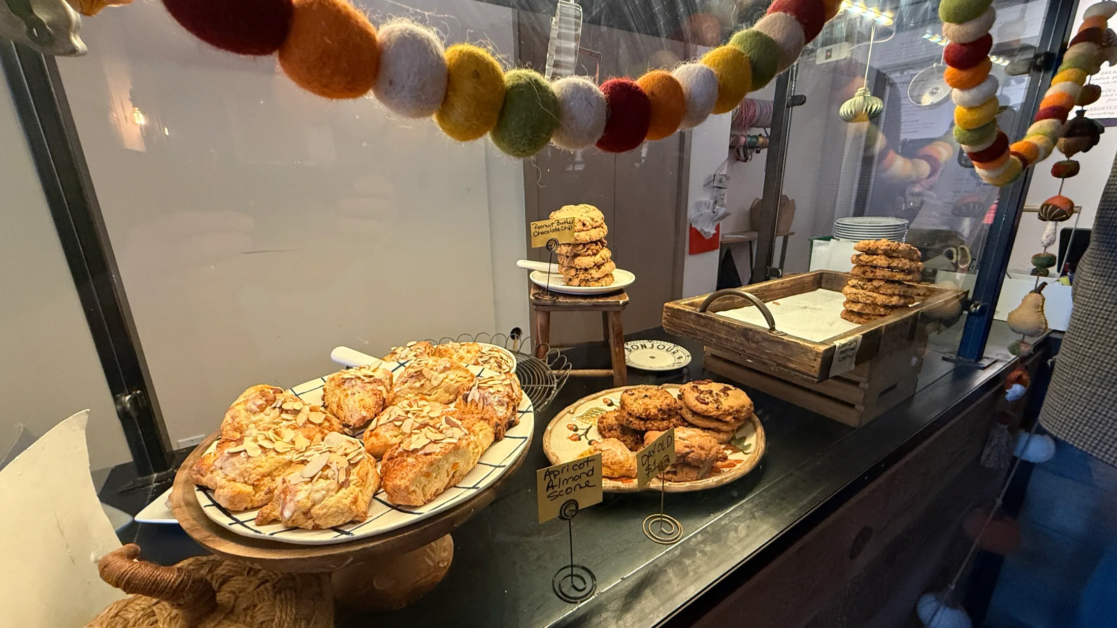 Henry & The Fish pastry case showing apricot almond scones, peanut butter chocolate chip cookies, and chocolate chip cookies on wooden serving boards