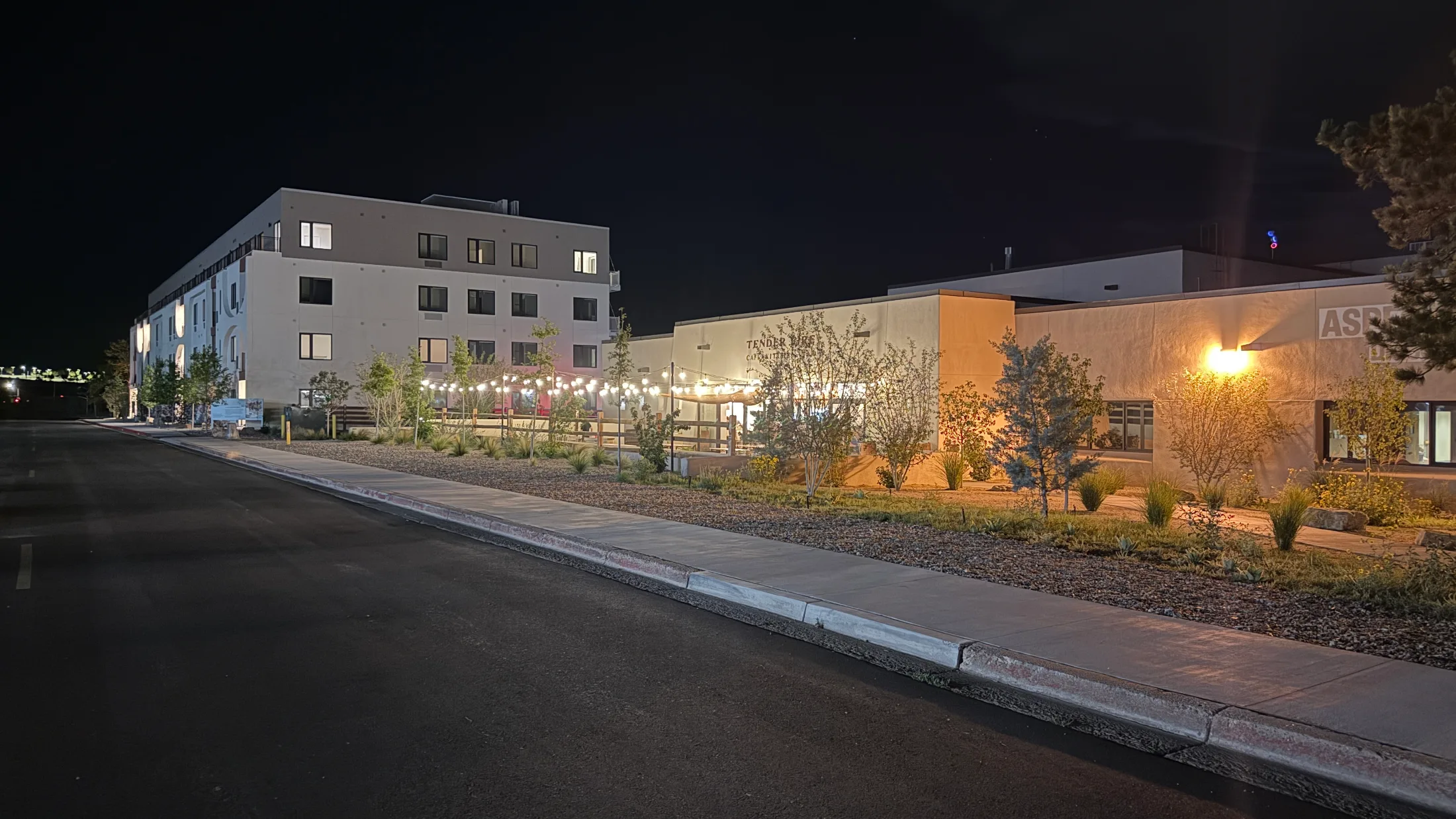 Night view of Aspect Media Village showing Tender Fire's lit patio and the Aspect building sign