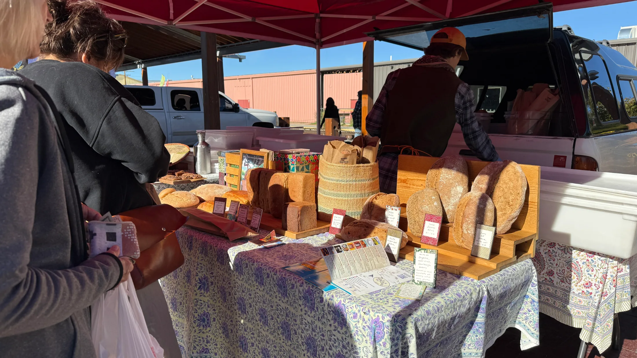 Artisan bread loaves displayed on wooden boards at an outdoor vendor table