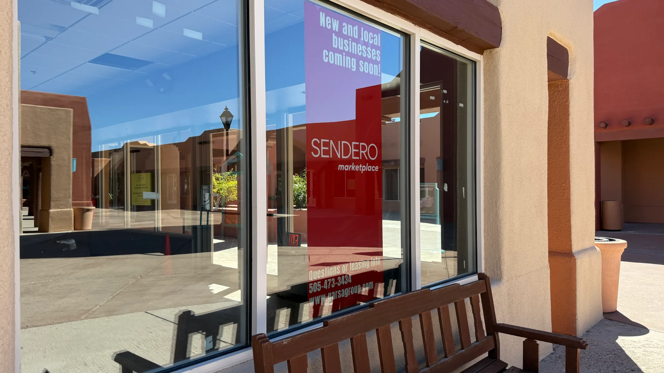 Window banner on an empty storefront reading New and local businesses coming soon, with Sendero Marketplace branding and leasing contact information