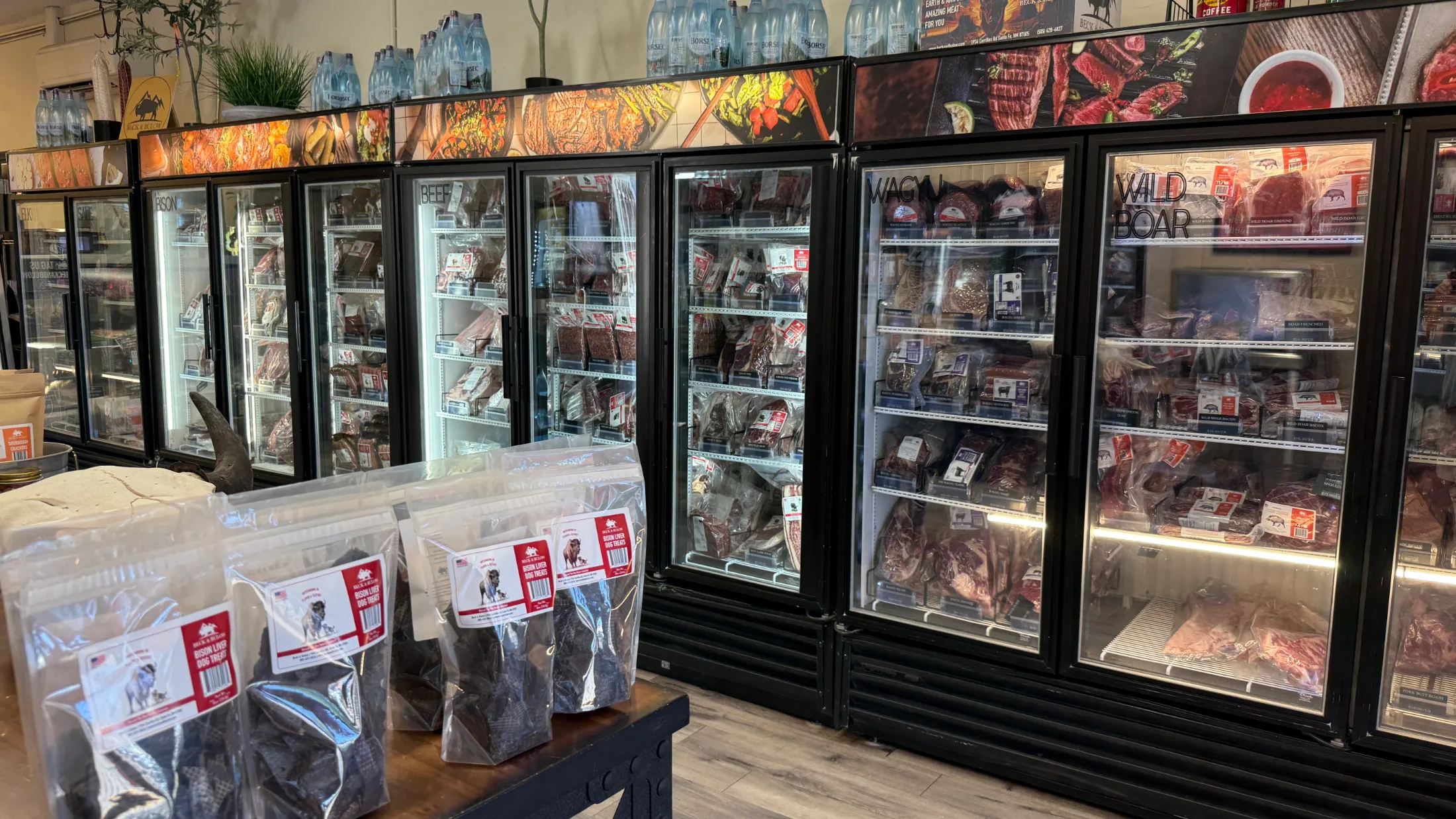 Row of freezer cases at Beck and Bulow labeled Bison, Beef, Wagyu, and Wild Boar, stocked with vacuum-sealed cuts
