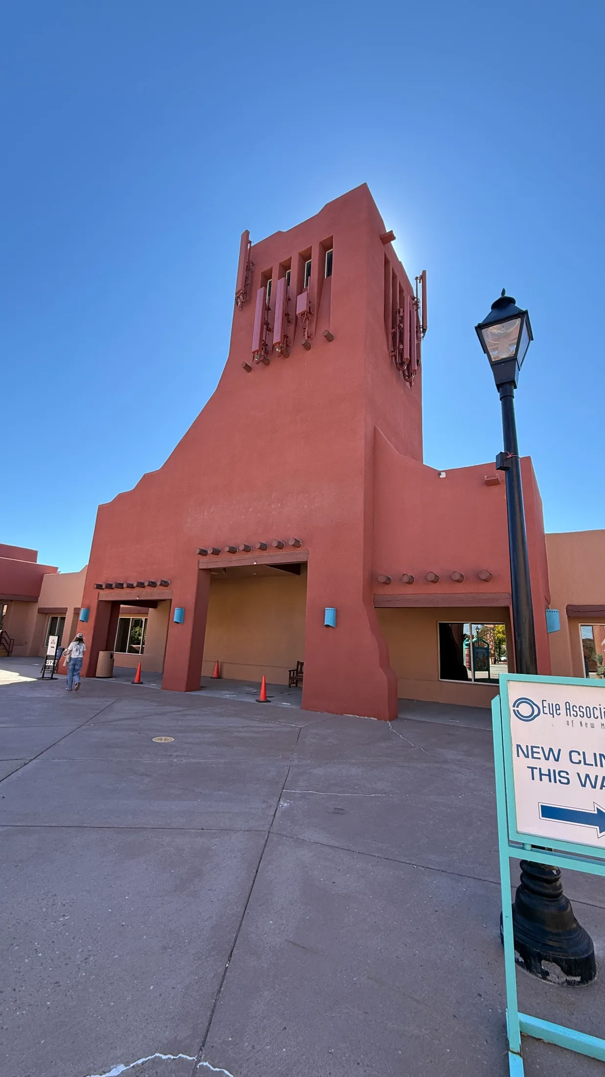 The tall red stucco tower at the center of the Sendero Marketplace property, with a lamp post and Eye Associates clinic signage in the foreground