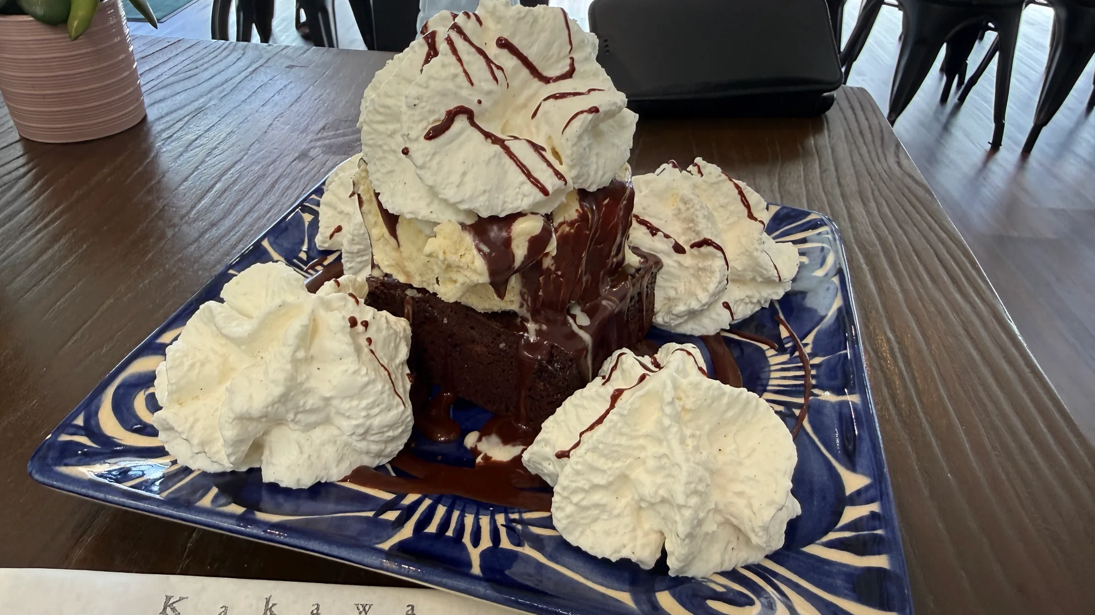 Kakawa brownie sundae on a blue Talavera plate topped with house-made ice cream, hot fudge, and billowing whipped cream