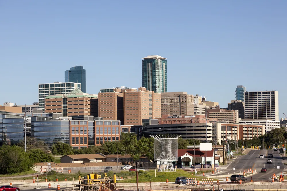 Fort Worth skyline on a clear day with a sculptural arch installation in the foreground