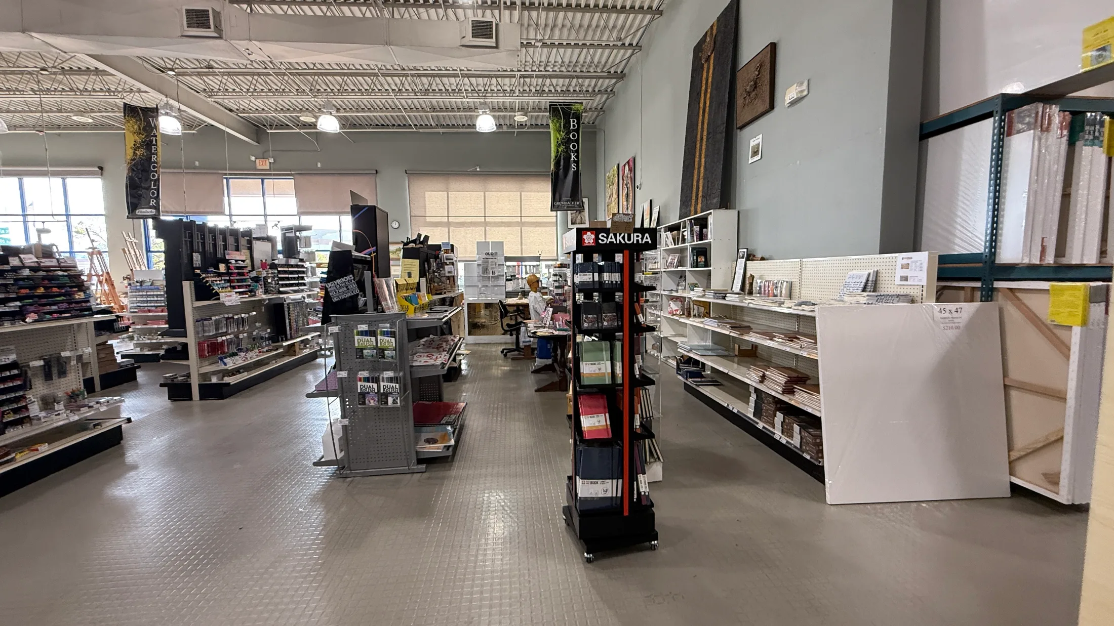 Artisan Santa Fe interior showing Sakura, Dual Brush, and Books displays with large pre-stretched canvases and a staff member at the counter
