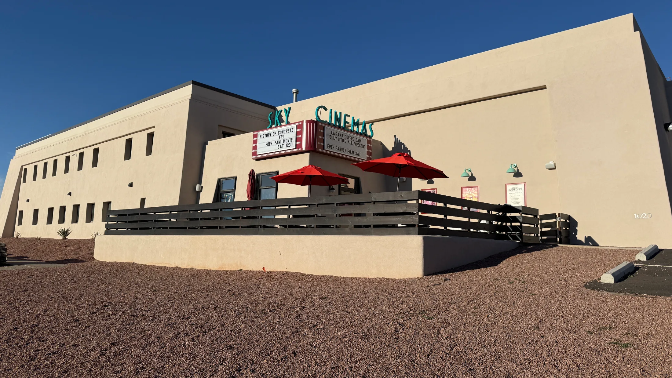 Sky Cinemas at 1020 Midtown Calle Central, marquee reads La Rana Coffee 8am, Happy Bday Konrad and Danny, Free Family Movie Sunday 12:30, red umbrellas on patio to the left, address 1020 visible on the stucco wall