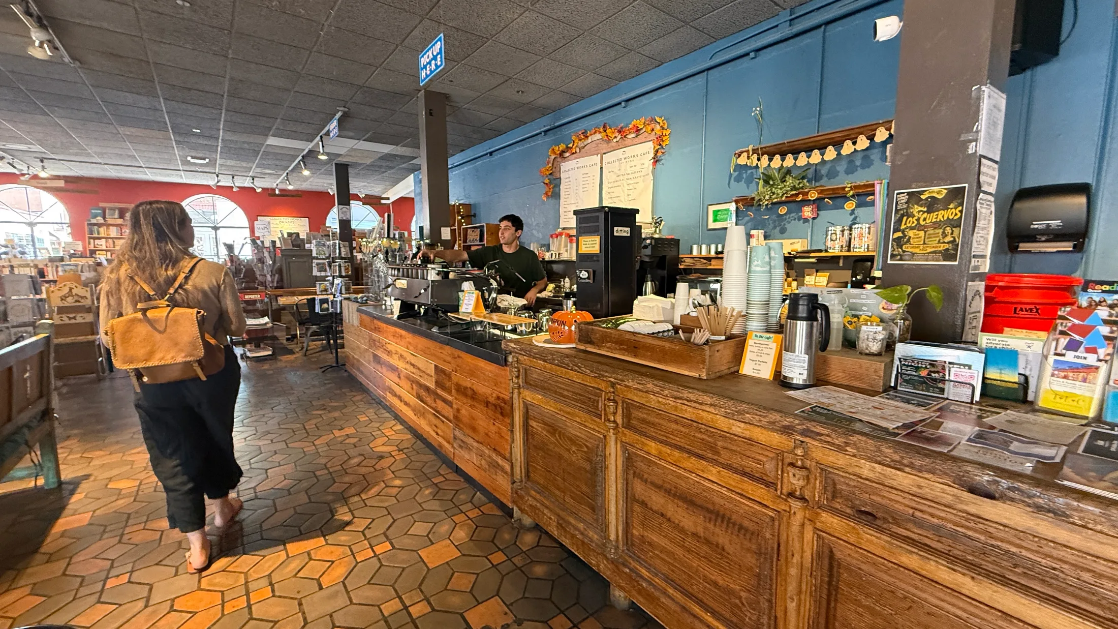 Café counter at Collected Works Bookstore, barista at espresso machine, reclaimed wood bar, customer approaching