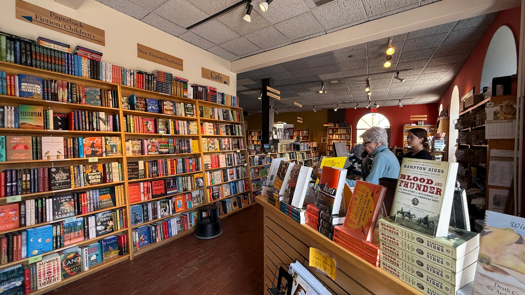 New fiction and nonfiction shelves at Collected Works, checkout counter with staff, Hampton Sides Blood and Thunder prominently displayed