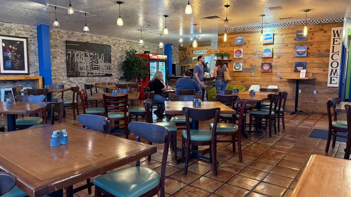 The Yamas dining room with stone and wood walls, pendant lights, the 'Our Happy Place' sign, and a handful of afternoon lunch guests