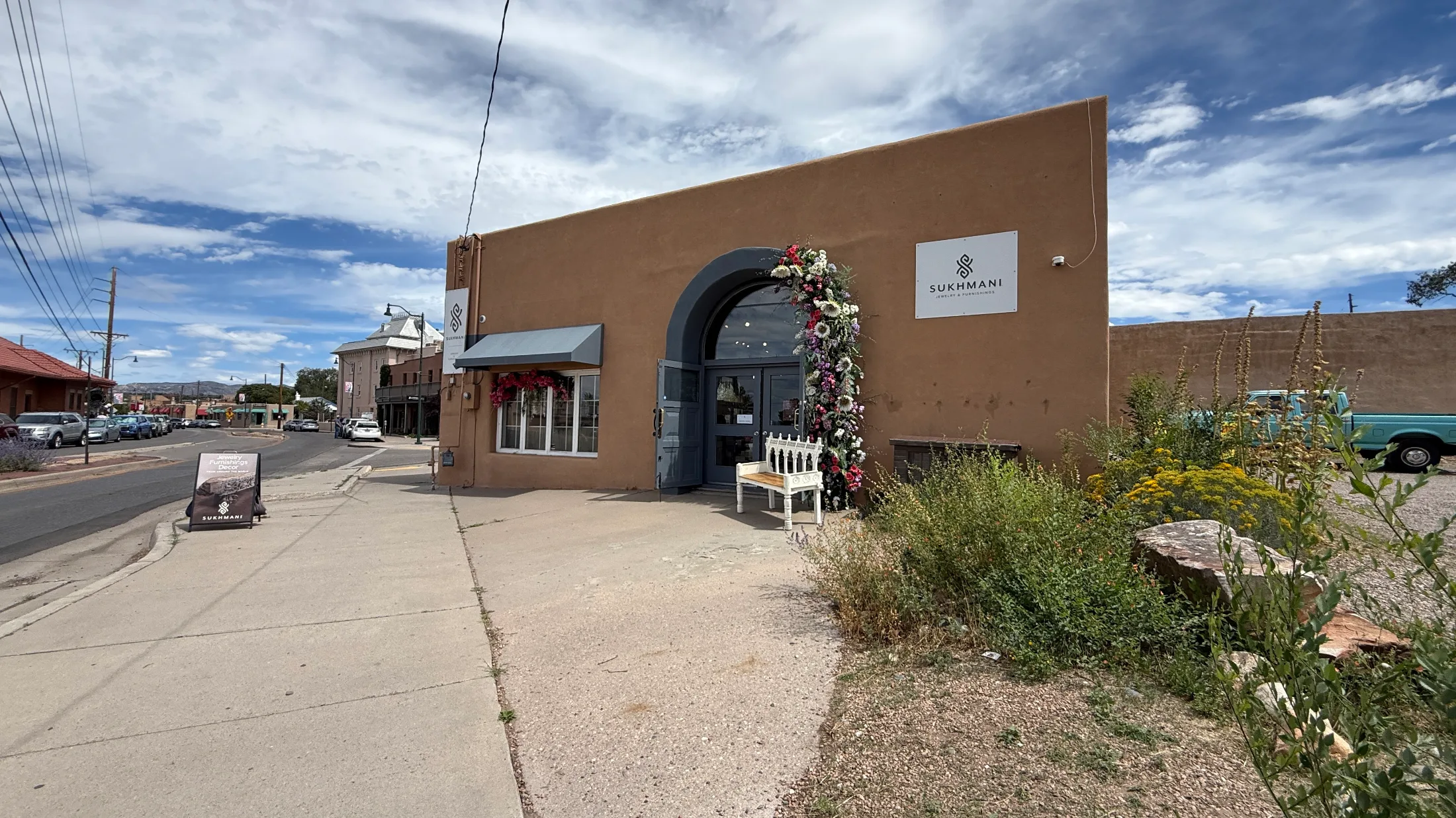 Exterior of Sukhmani Santa Fe on Read Street — adobe facade with arched entrance, flower wreath, and Sukhmani Jewelry and Furnishings signage