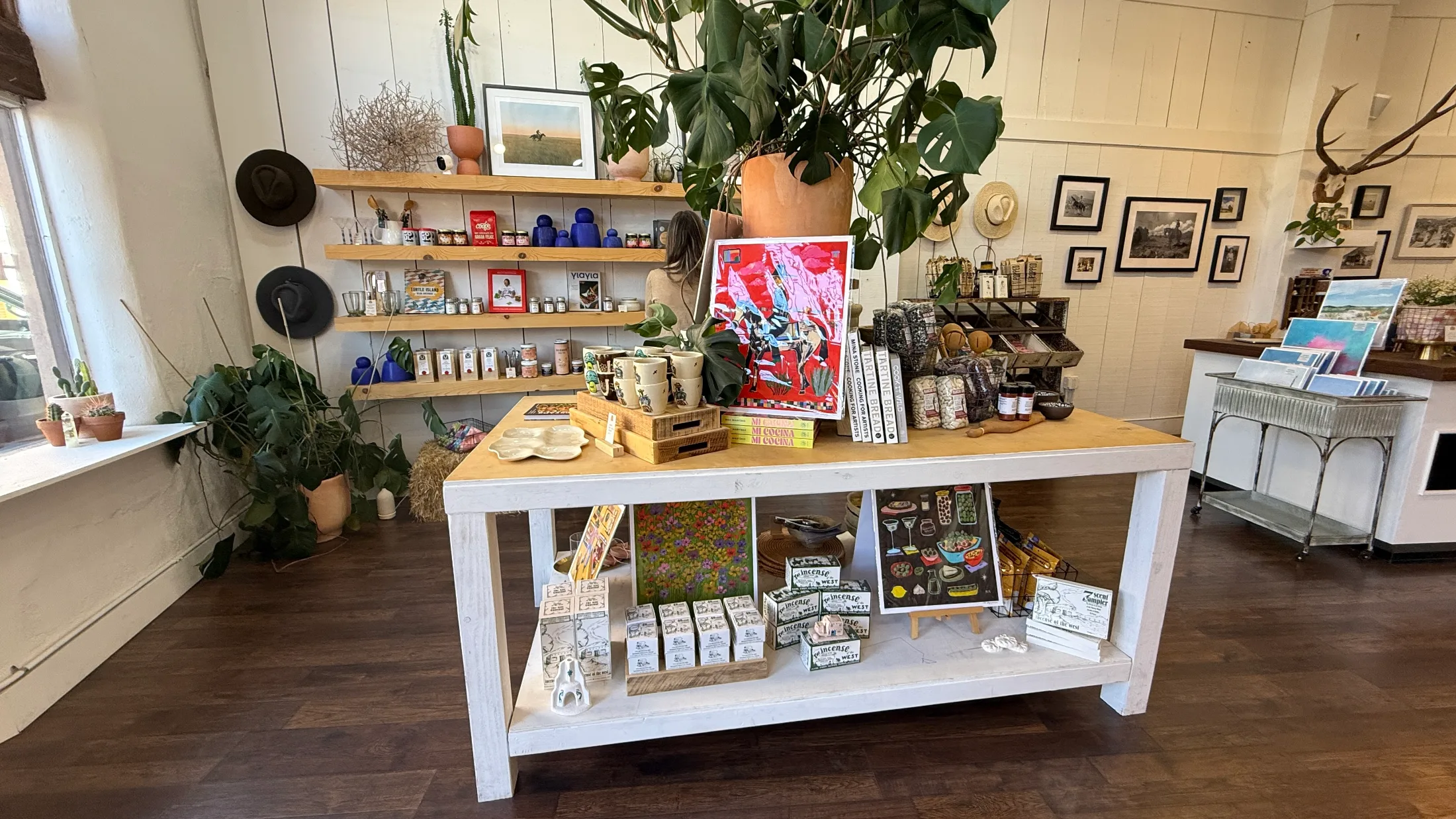 Central display table at High Noon General Store with cookbooks, incense boxes, art prints, and ceramics