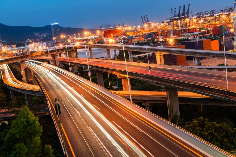 Aerial view of highway interchange at night with light trails from moving vehicles