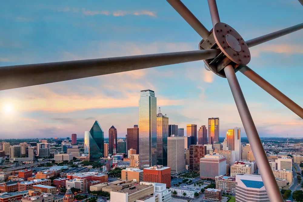 Dallas skyline at sunset viewed through steel structural beams, Reunion Tower visible