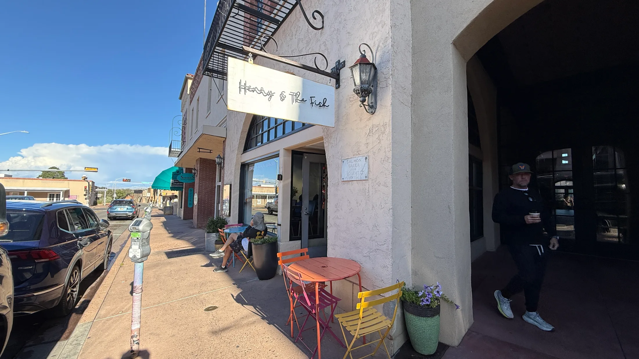 Exterior of Henry & The Fish on West San Francisco Street, Santa Fe, with colorful orange and yellow sidewalk tables in the sun