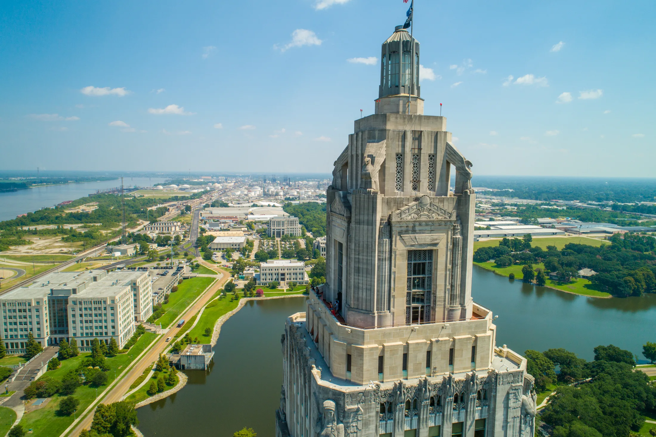 Aerial view of the Louisiana State Capitol tower with the Mississippi River and industrial corridor behind it