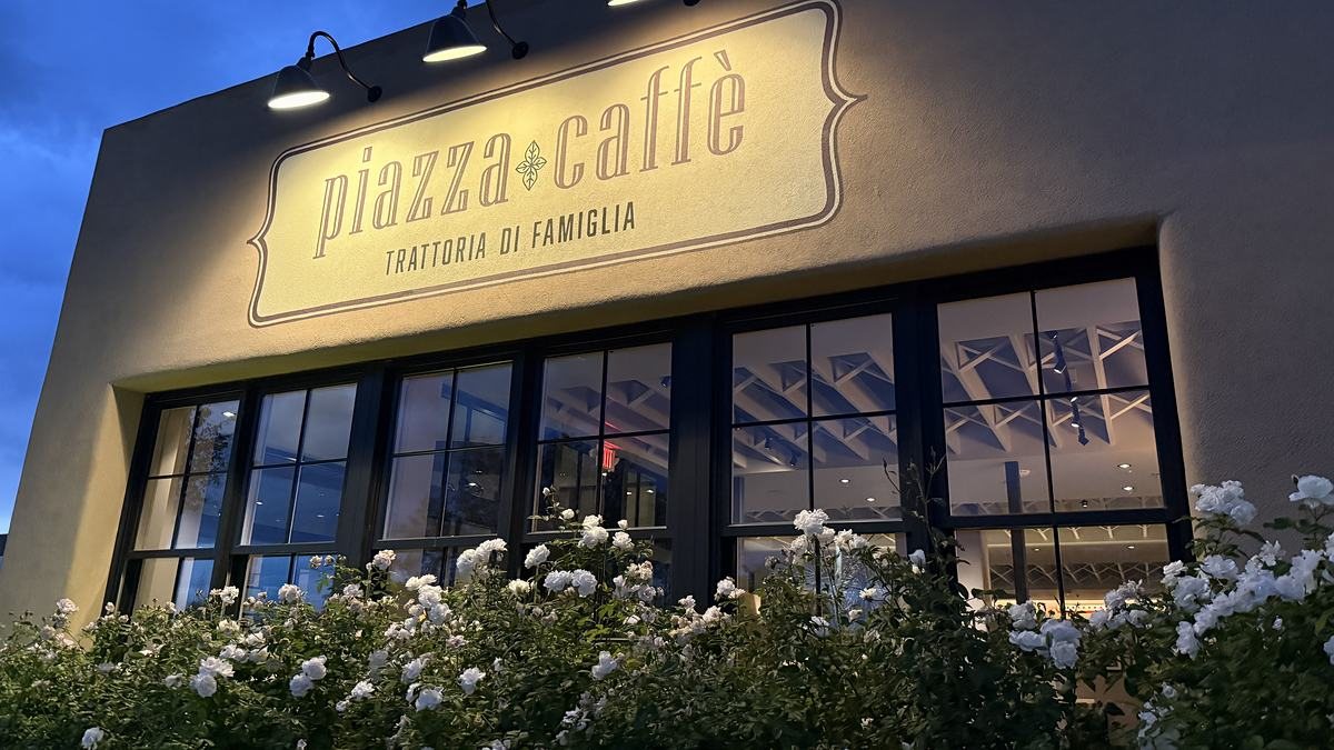 The Piazza Caffe sign on Camino Entrada at dusk