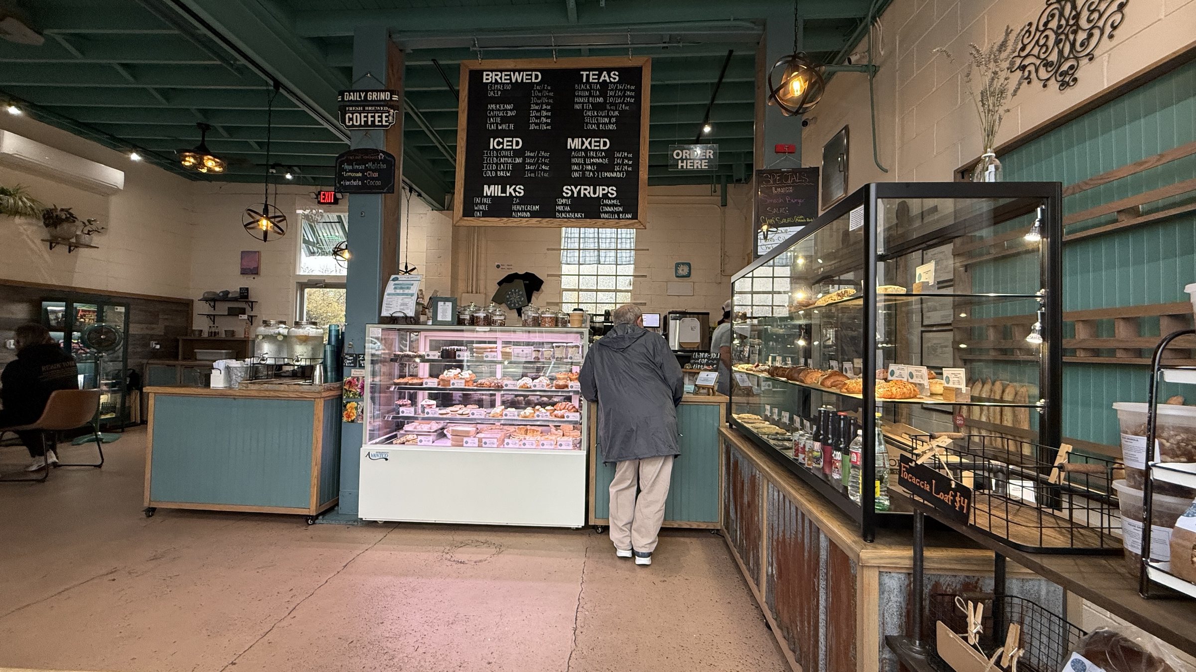 Wide view of the counter, bakery cases and chalkboard drink menu inside Baked and Brew