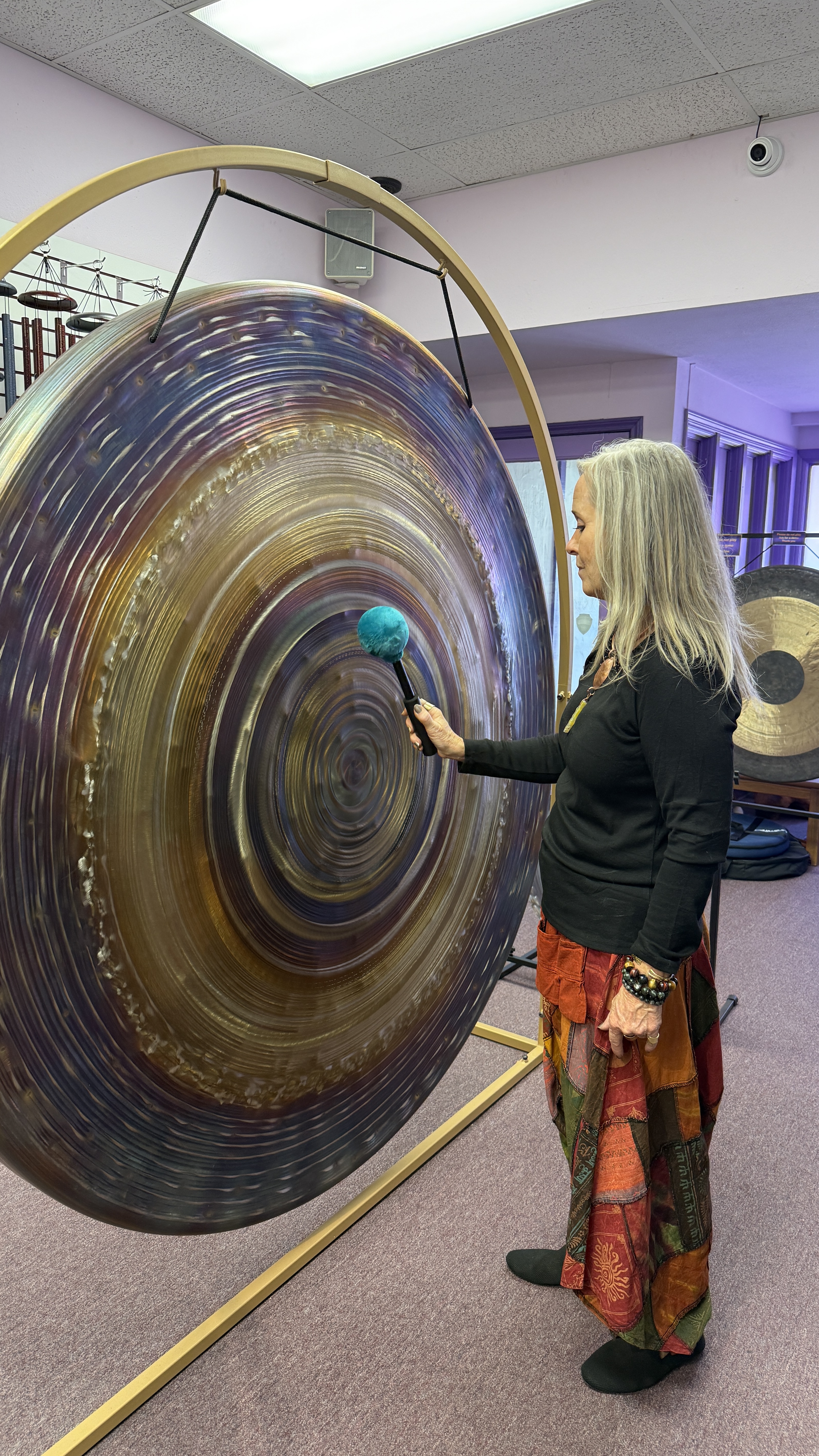 Katherine at a large iridescent gong with a turquoise mallet