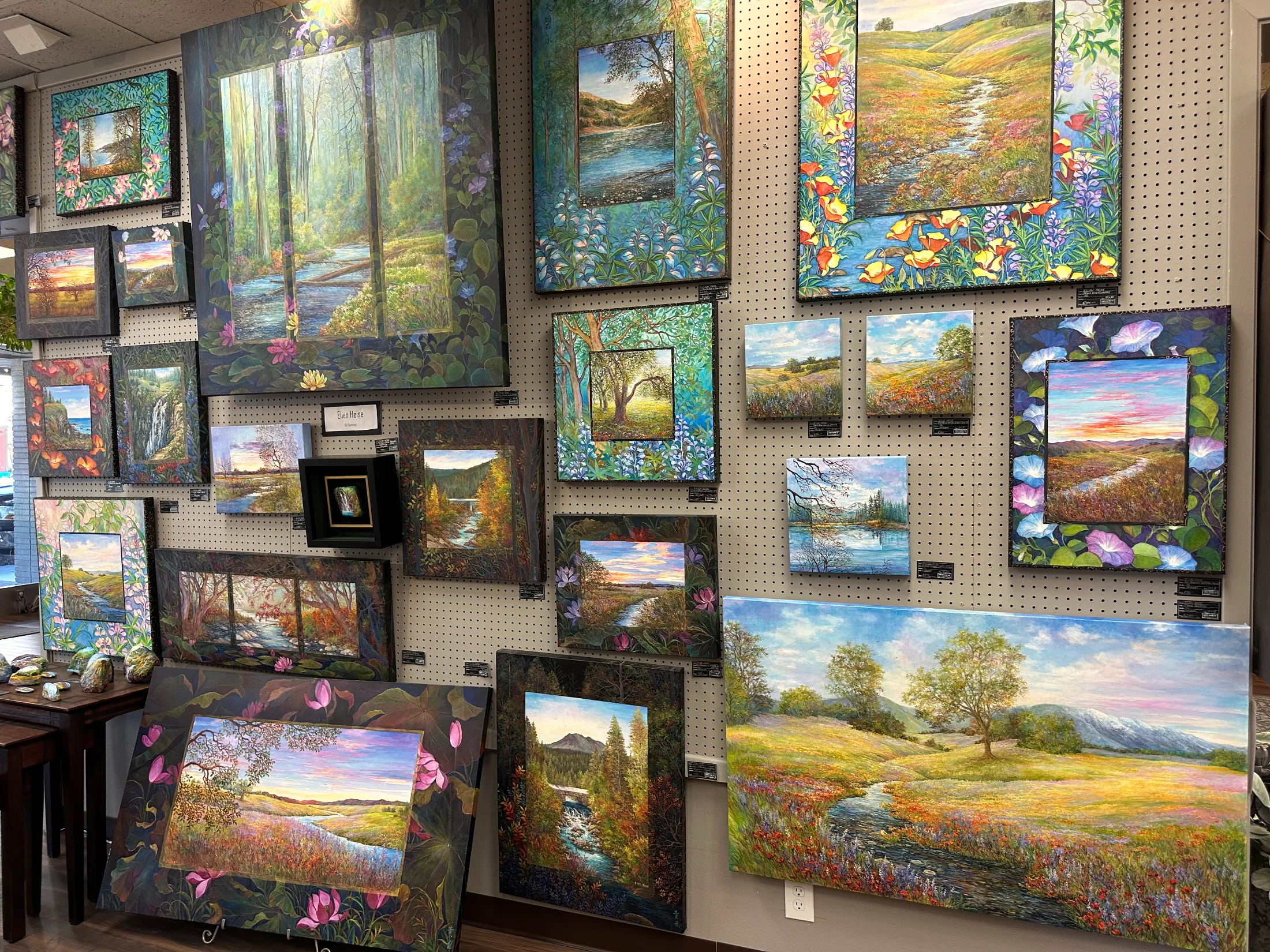 Wall of colorful landscape oil and acrylic paintings inside Chico Paper Company