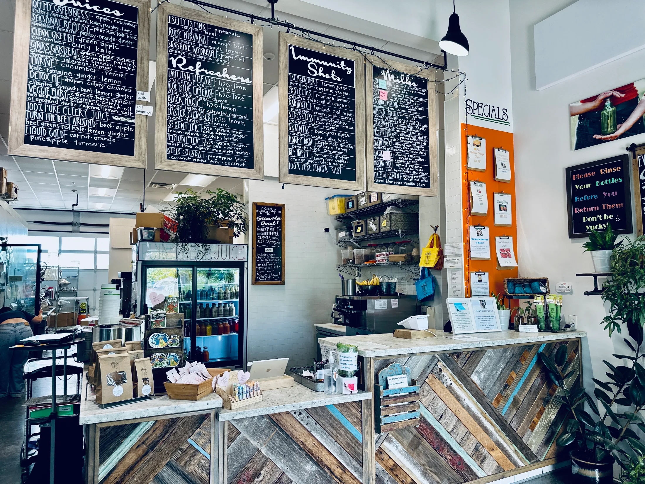 Interior of Live Life Juice Co. showing chalkboard menu boards covering juices, refreshers, immunity shots, and milks
