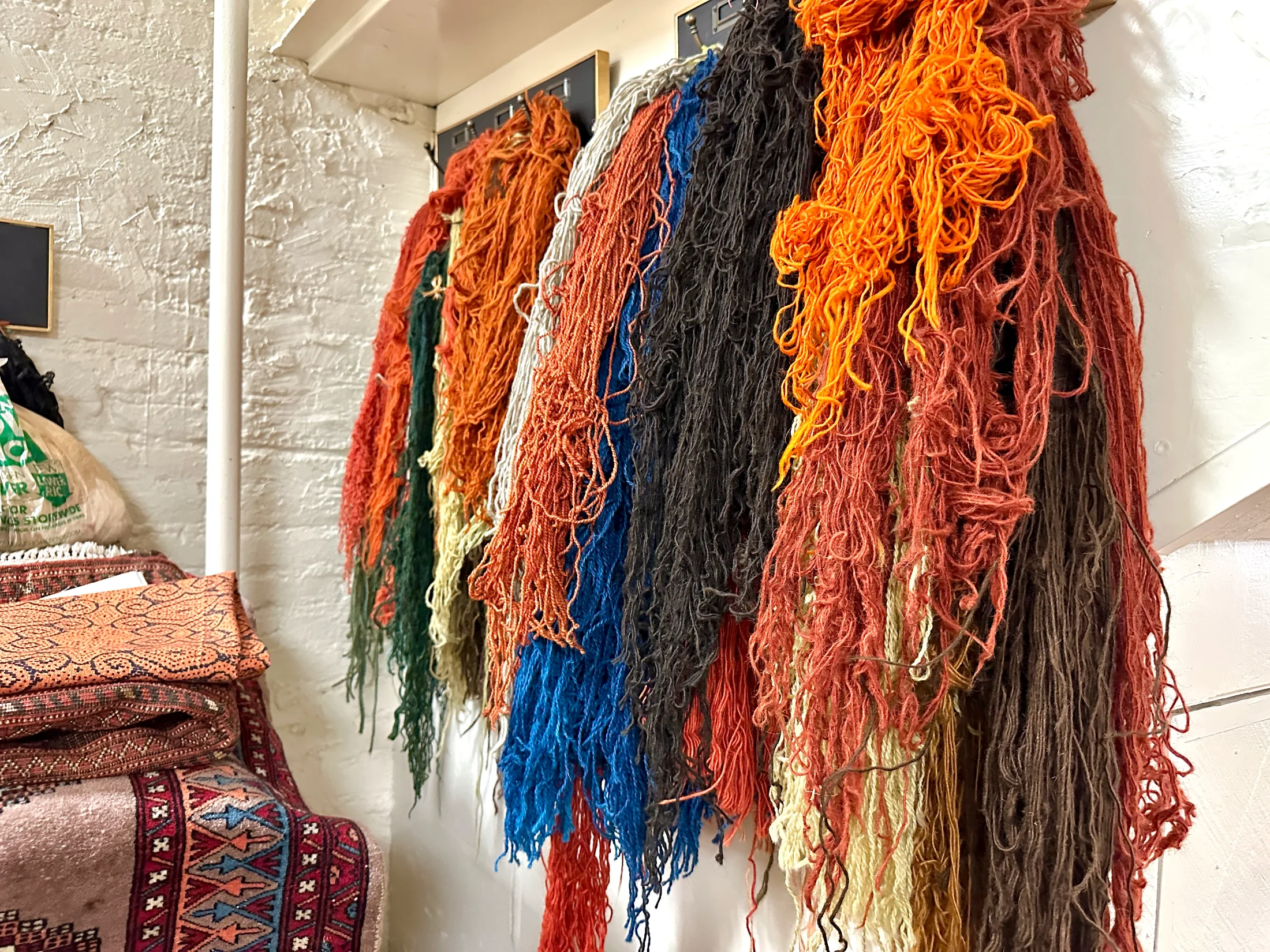 Skeins of organically dyed wool in rich colors hanging on the wall inside Pasha Hand Crafted Rugs