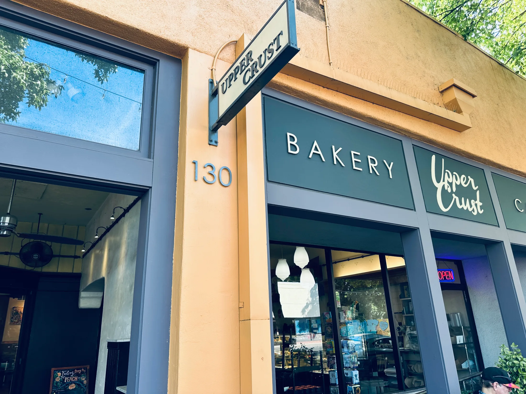 Upper Crust Bakery storefront at 130 Main Street in downtown Chico, deep teal signage with a chalkboard outside