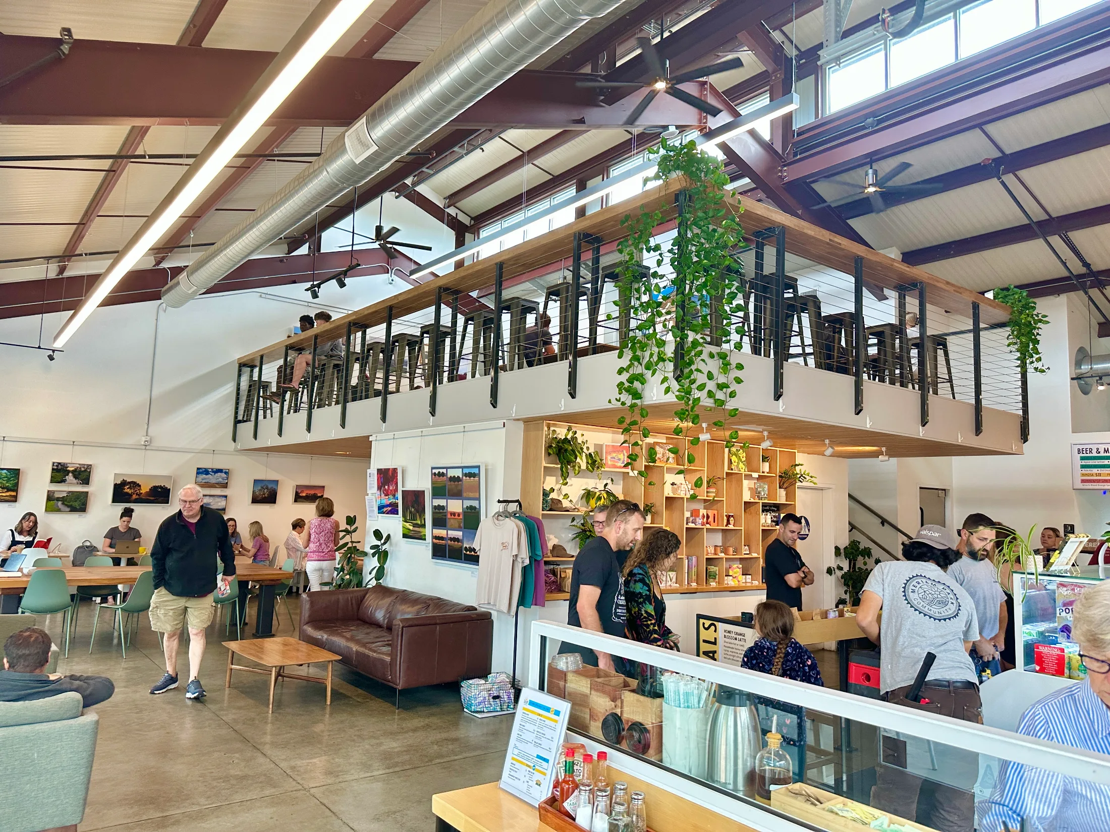 Interior of Daycamp Coffee showing the lofted mezzanine level above the main floor, filled with people working and visiting