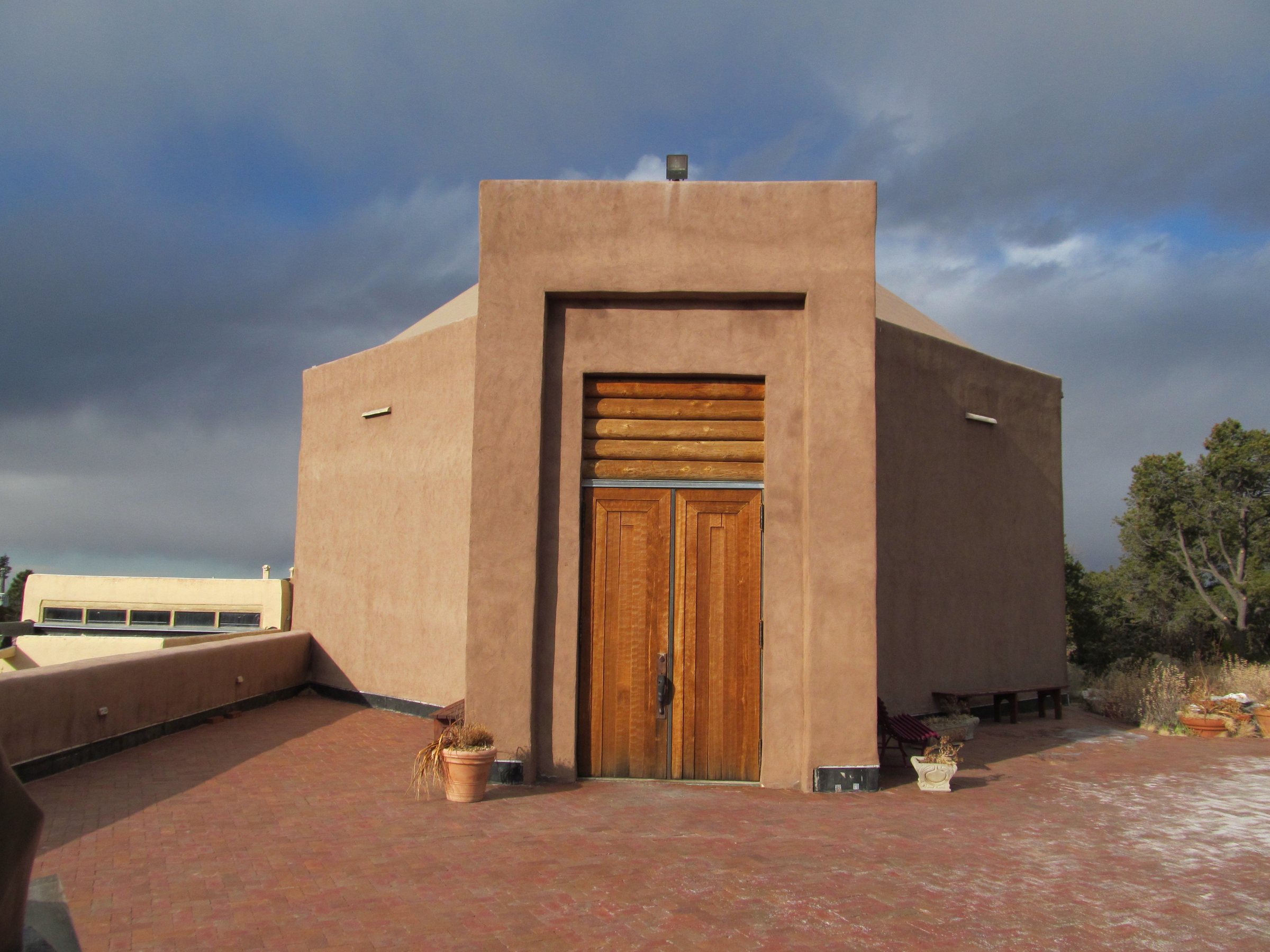 The Wheelwright Museum of the American Indian, a tan building with a wooden double door on a brick terrace