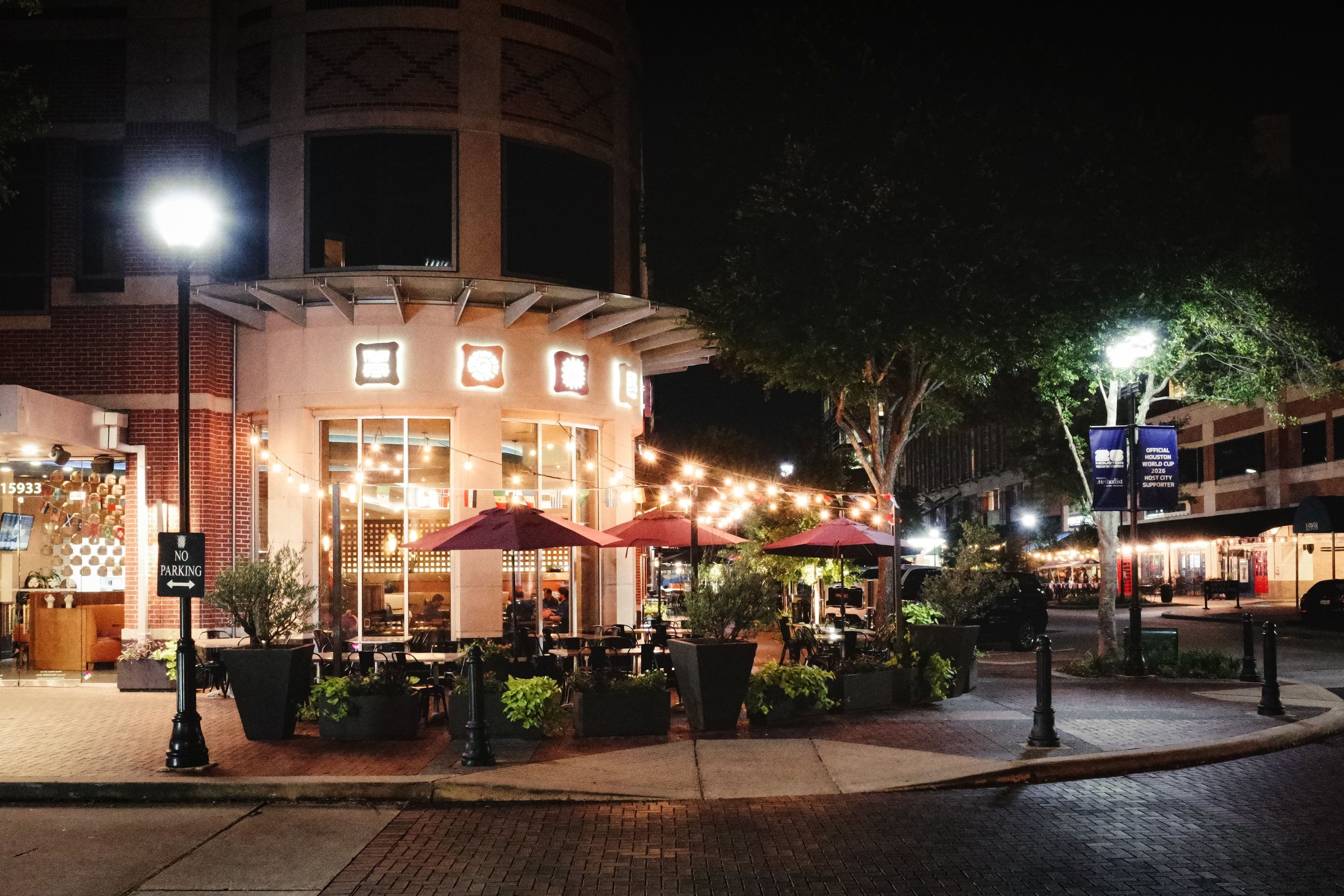 Outdoor dining at night in Sugar Land, Texas, with string lights and colorful umbrellas
