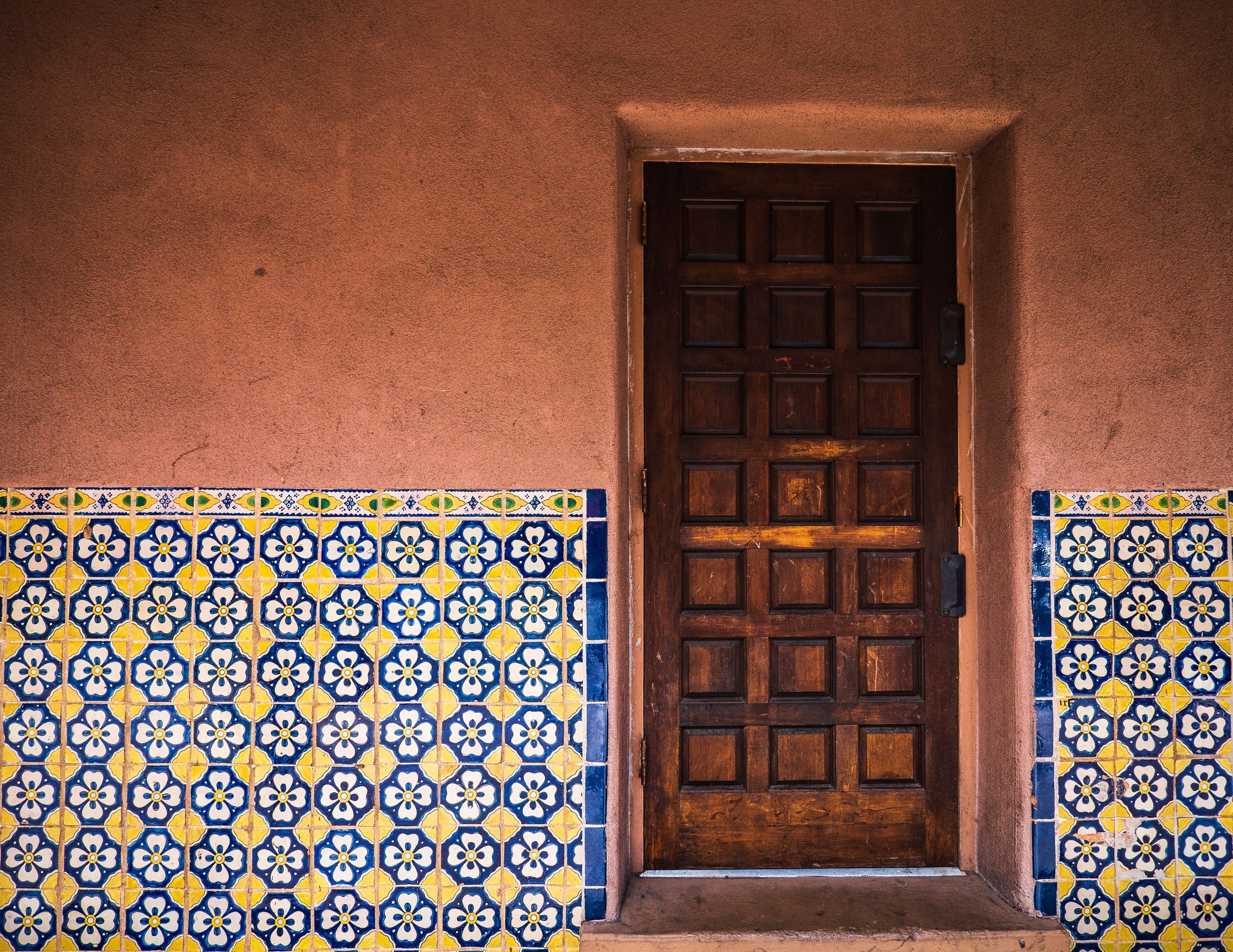 Rustic wooden door with vibrant patterned tiles in Santa Fe