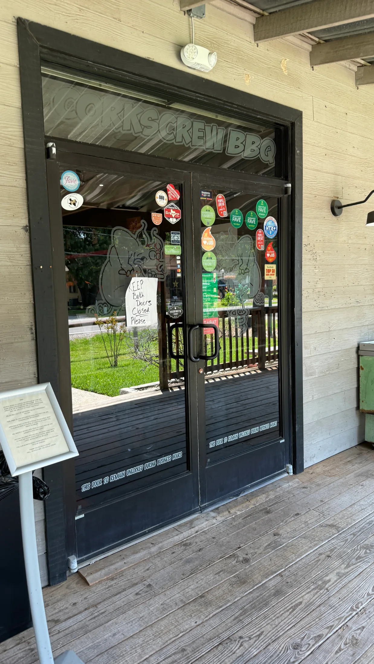 Front entrance of Corkscrew BBQ in Spring, Texas, glass doors covered in award stickers