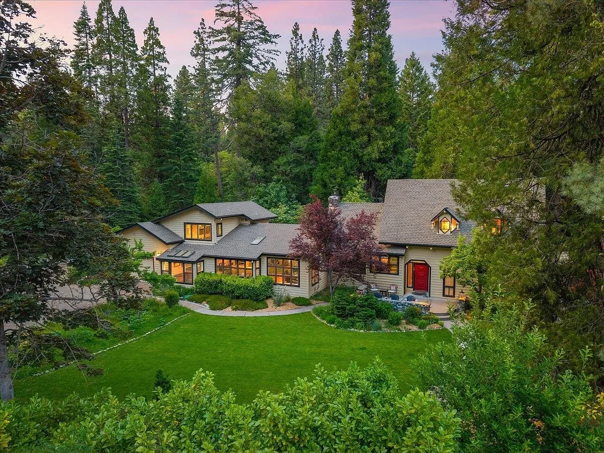 Twilight aerial of 1405 Audubon Rd with lights glowing through large windows, surrounded by lush landscaping