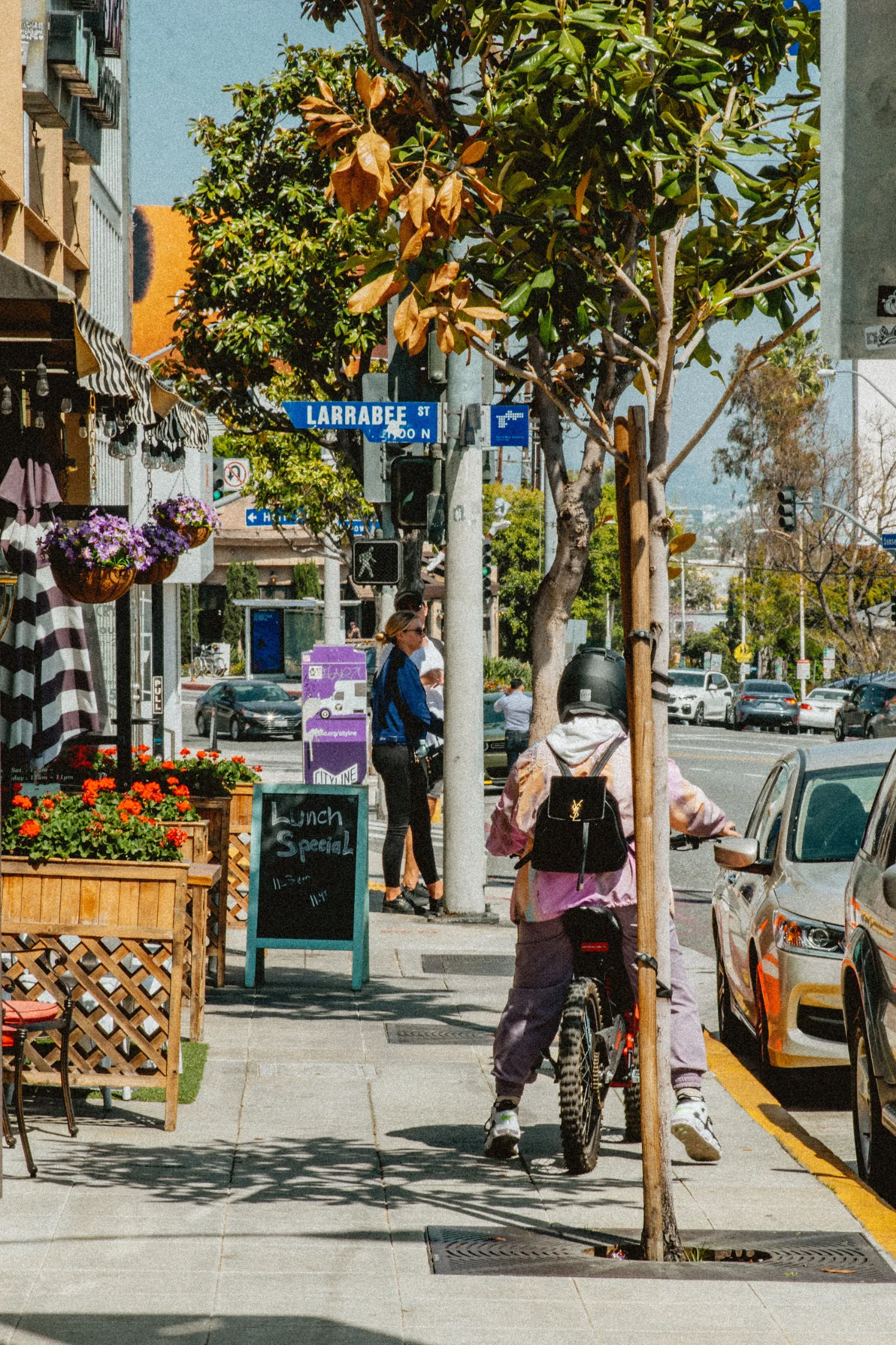 E-bike rider in West Hollywood at Larrabee Street with lunch spot patio in foreground