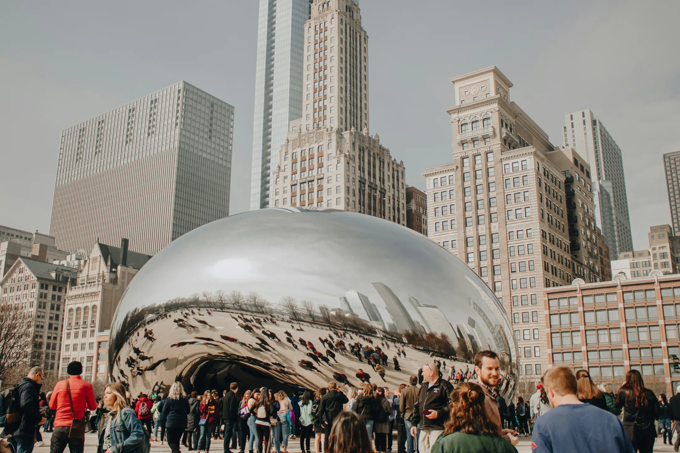 Crowds gathering around Cloud Gate at Millennium Park with the Chicago skyline behind