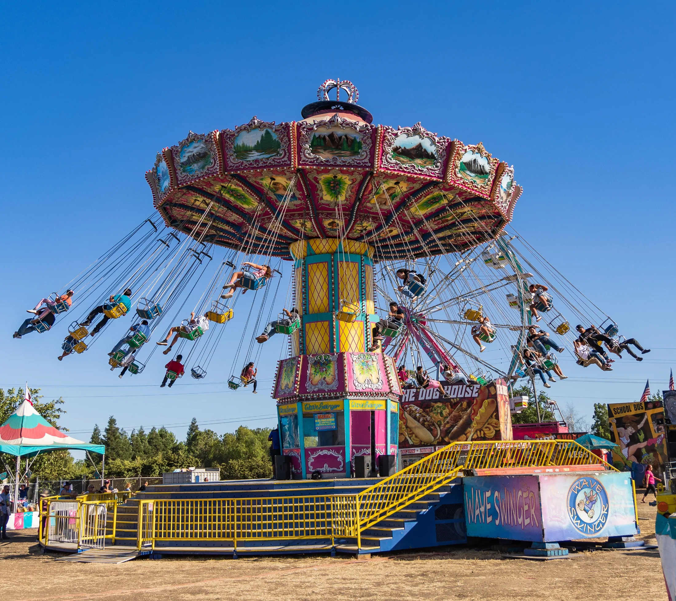 Wave Swinger ride spinning riders high in the air against a blue summer sky at the California State Fair