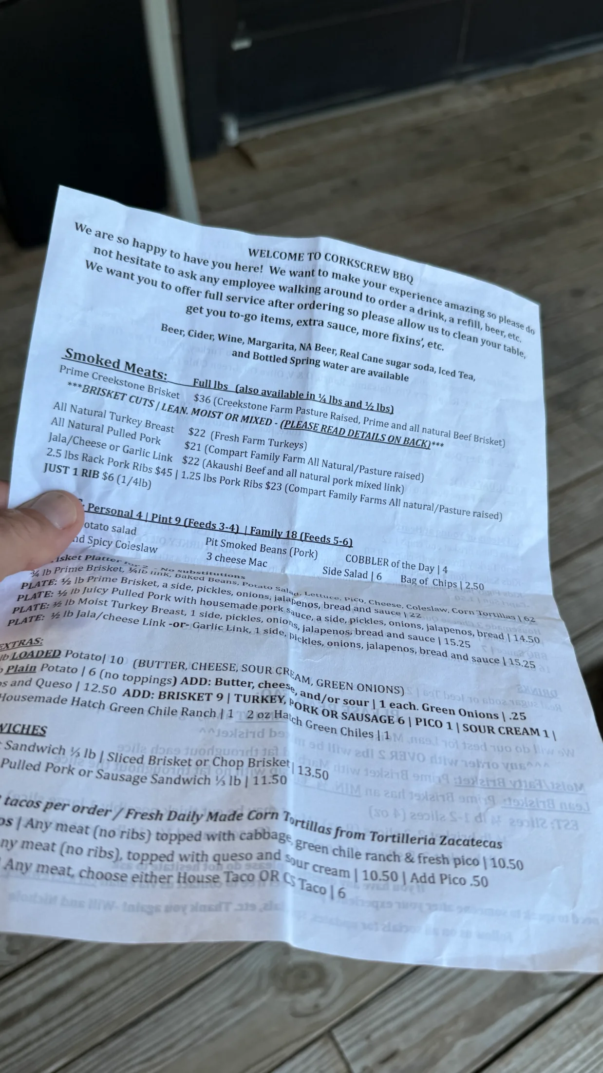 Corkscrew BBQ menu sheet showing smoked meats prices, sides, tacos, and sandwiches