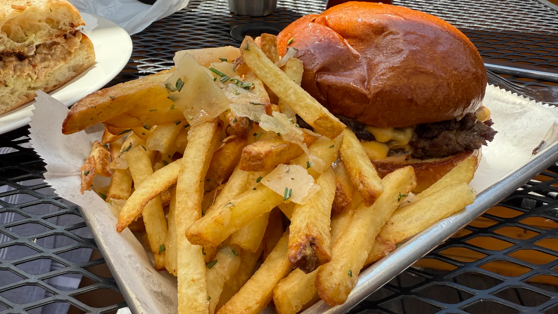 Pipeline Classic burger on a brioche bun with a pile of duck fat fries on a metal tray at Pipeline Craft Taps