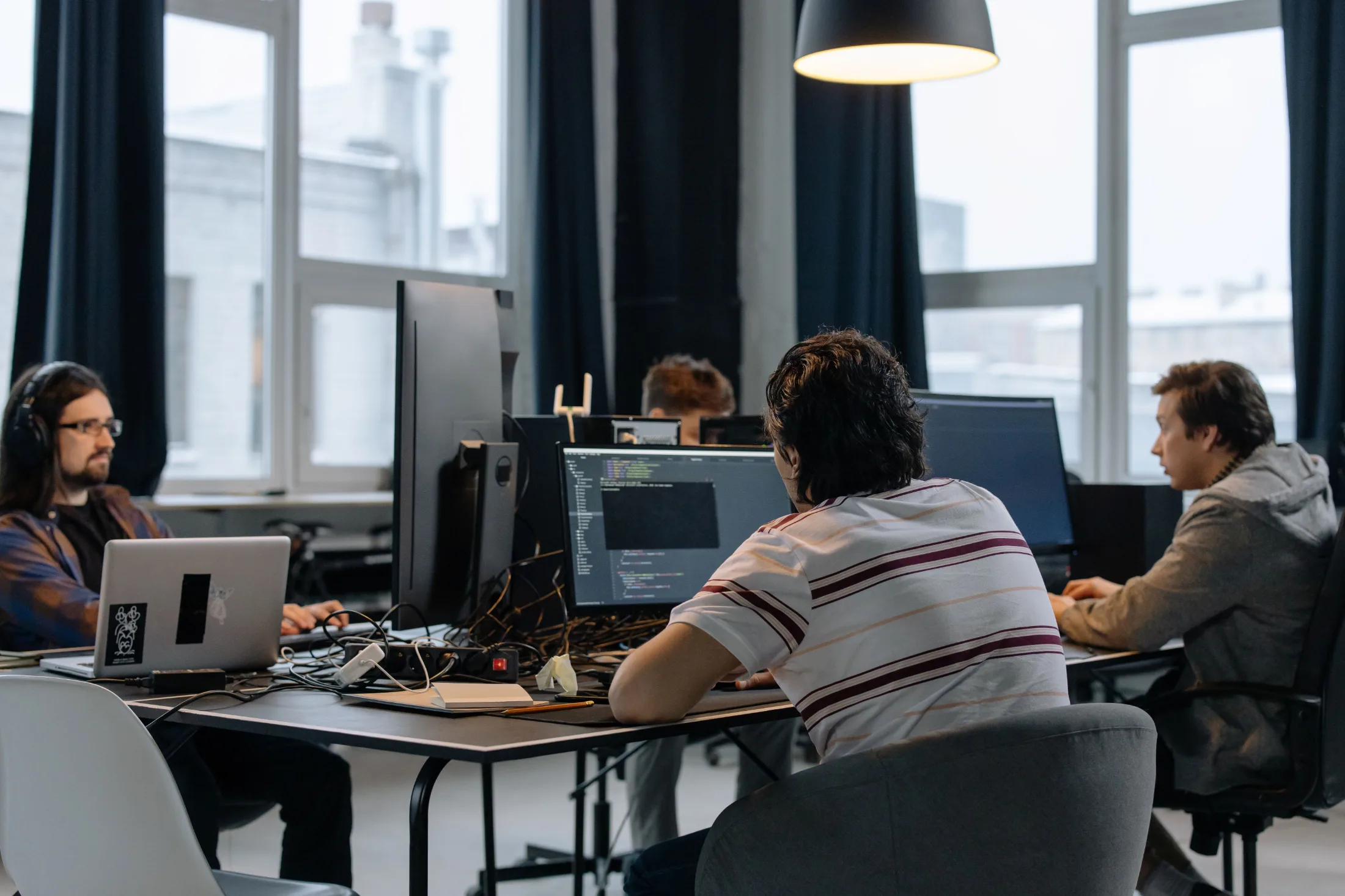 Developers working at monitors with code on screen in a bright open office