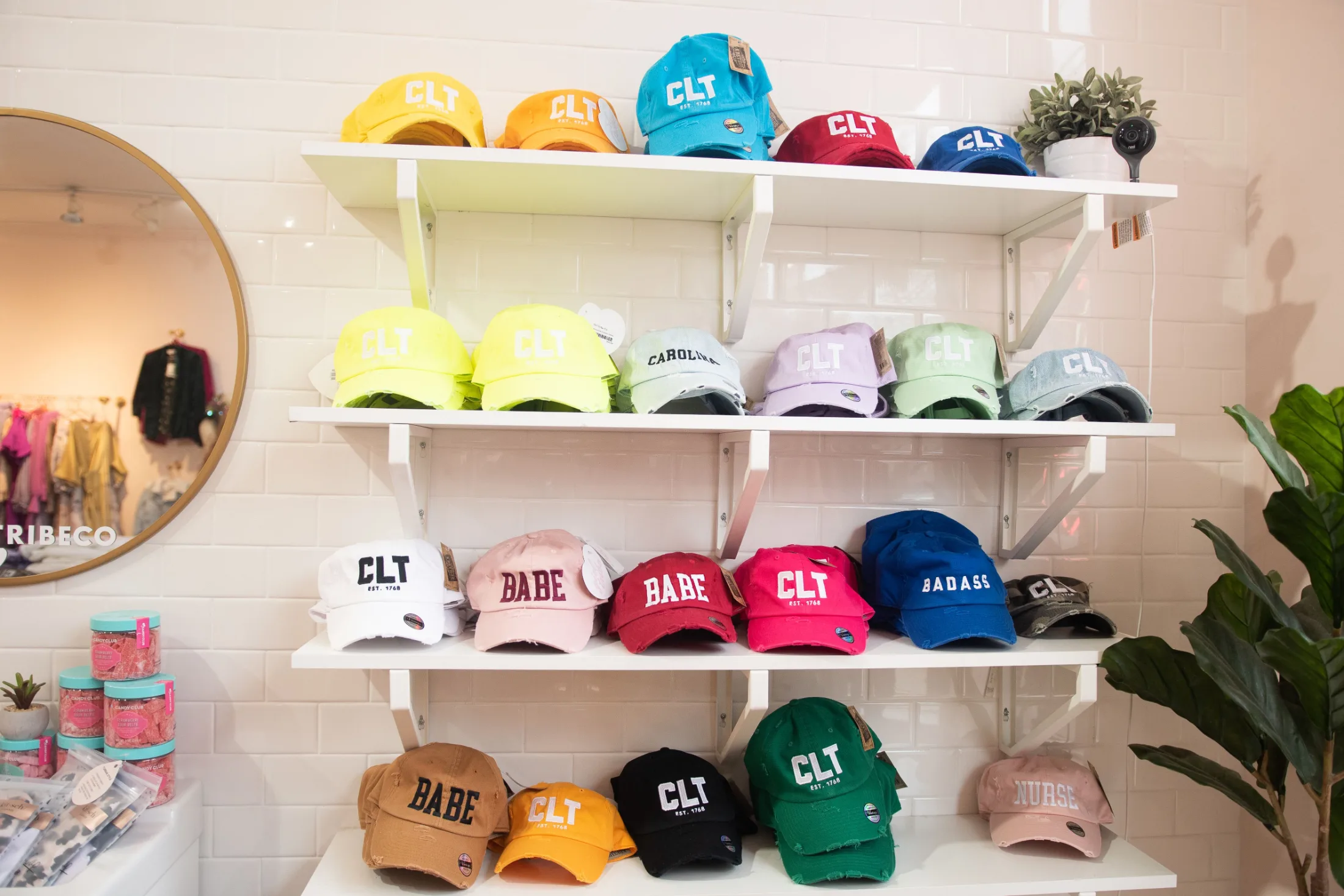 Shelves of colorful CLT-branded hats in a local Charlotte shop, signaling the city's casual pride of place