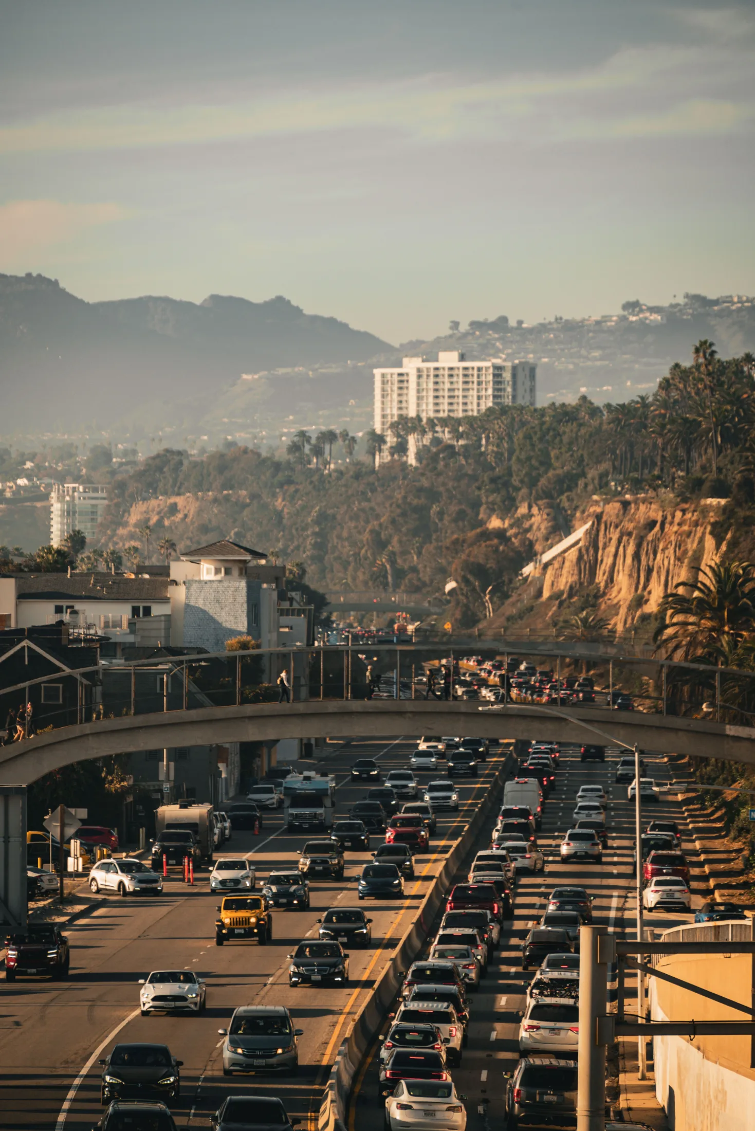 Dense LA freeway traffic at golden hour with hillside backdrop