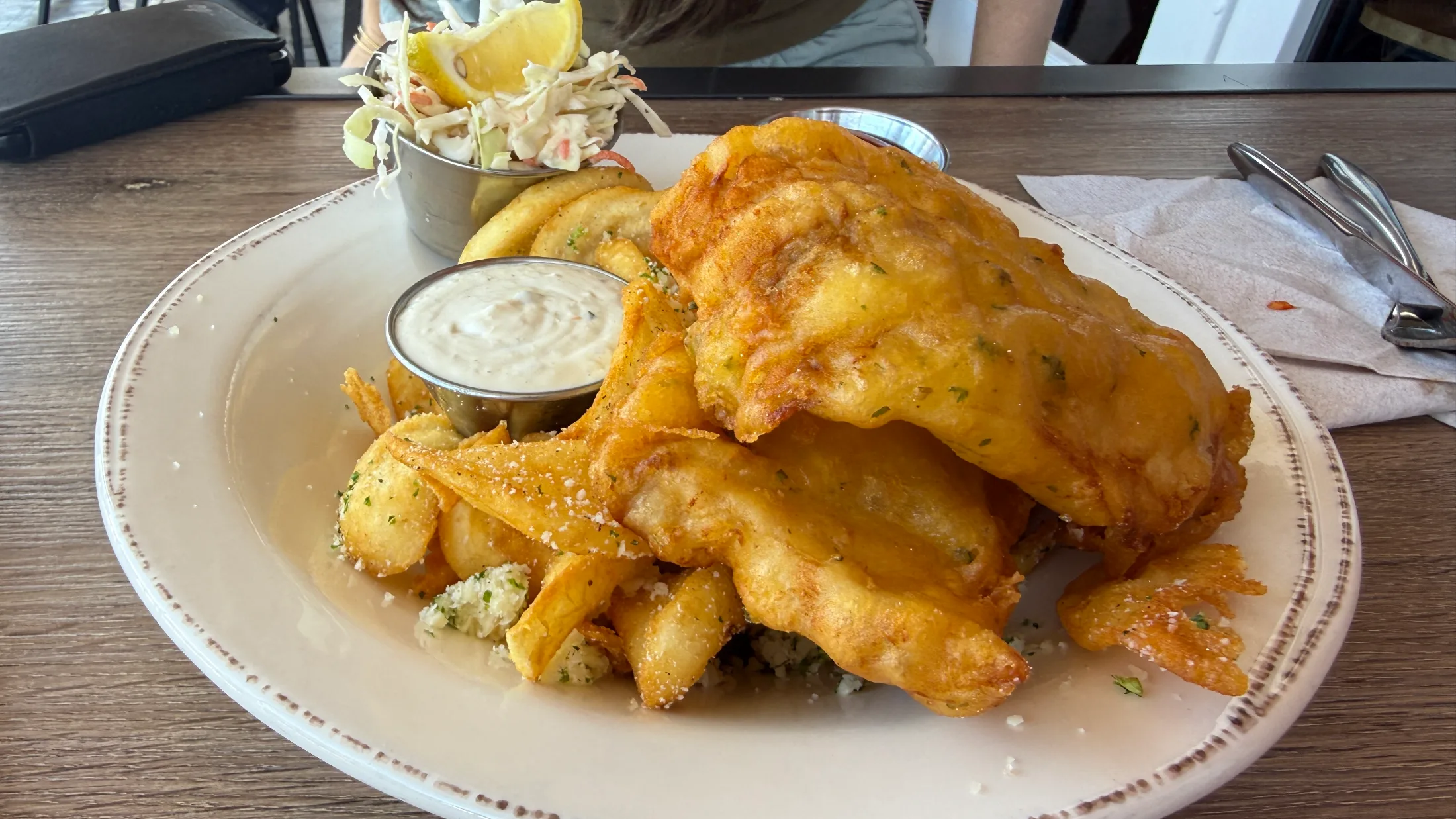 Denny Bar Company fish and chips — golden beer-battered fish over herb-dusted fries with coleslaw and tartar sauce