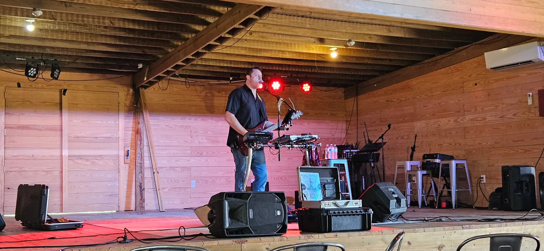Live musician performing on the DeepRoots Vineyards barn stage under red stage lighting